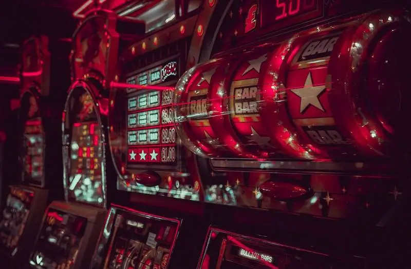 Close-up gulungan mesin slot yang sedang berputar dengan simbol BAR dan bintang di bawah cahaya merah